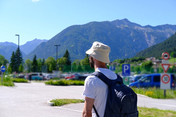 Fototapeta na wymiar young man 30 years old, backpacker in panama, tourist with blue backpack on back walks along road with magnificent natural scenery, high alpine mountains, watching nature, travel, summer vacation