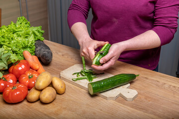 Woman peeling a cucumber in her kitchen