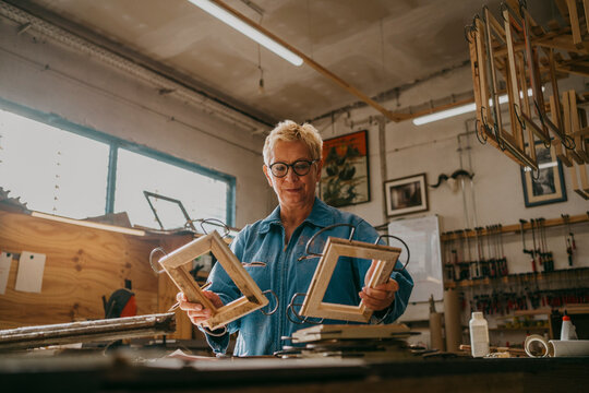 Low angle view of senior craftswoman examining frames at workshop
