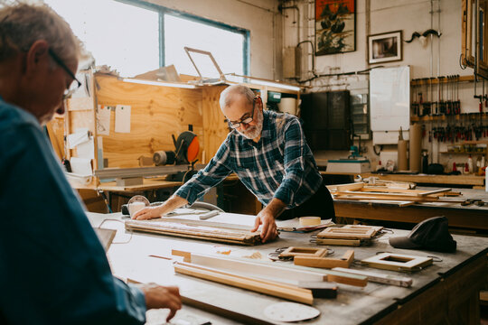 Senior male carpenter examining timber on workbench at repair shop