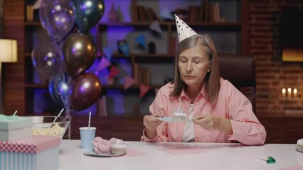 Lonely Elderly Woman Blowing Candle on Piece of Cake, Celebrating Birthday Alone. Mature Lady Feeling Unhappy, Sitting Lonely in the Nursing Home. Drama, Isolation, Old Age