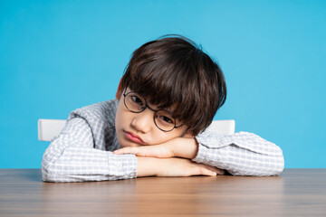 portrait of school boy sitting and studying on a blue background