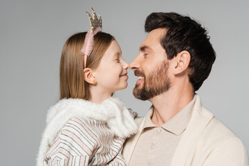 cheerful father and happy daughter touching noses isolated on grey.