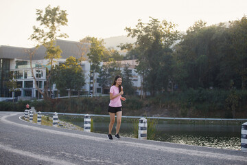 Beautiful Healthy woman running jogging in the park in the morning. She smiled and enjoyed. Healthy active lifestyle concept.
