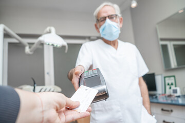 Adult woman paying for visit in dentist office in the medical clinic with card