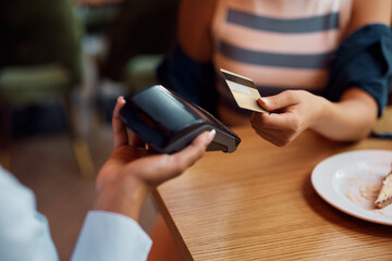 Close up of woman paying with credit card in restaurant.