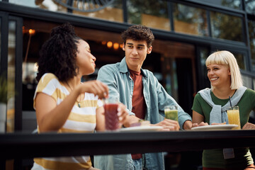 Young happy people talk while gathering in cafe.