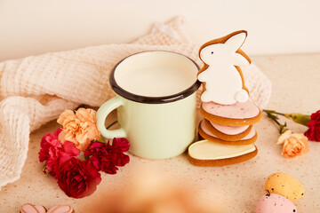Aesthetic milk mug with cute rabbit cookies and flowers. Springtime holiday floral background.