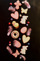 Obraz na płótnie Canvas Aesthetics springtime Easter glazed cookies decorated feathers on black background. Happy Easter banner