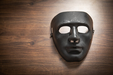 Black mask on the wooden table.