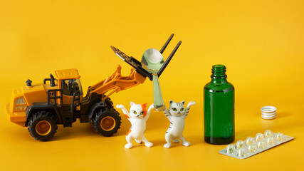 Funny toy kittens and forklift transport a teaspoon to an open green bottle of medicinal syrup....