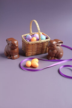 Chocolate bunnies, and Easter eggs in a small antique basket, with space for text.