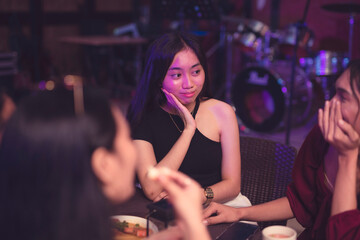 A young Asian lady concentrates in listening to her friend talking as she is invested with the topic about love life. Friendship bonding. - obrazy, fototapety, plakaty