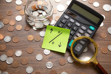 Percentage symbol on sticky note with a coins and calculator.