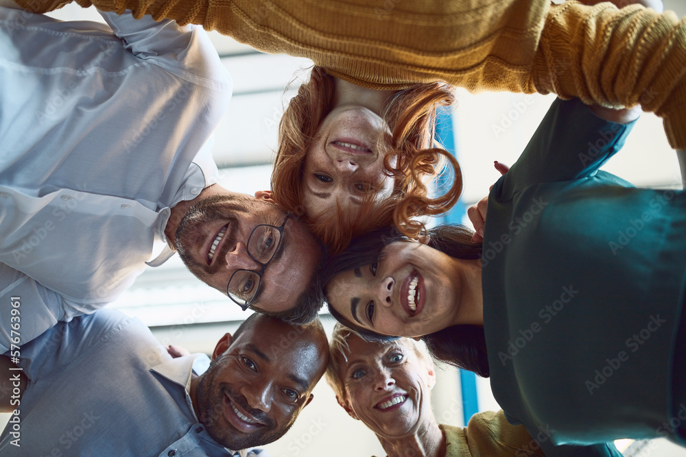 Poster surrounded by like minded go getters. low angle shot of a group of colleagues huddled together in so