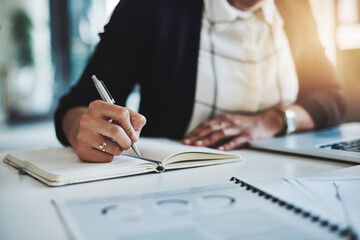 Fototapeta premium First plan is to be productive. Cropped shot of a businesswoman making notes at her desk in a modern office.