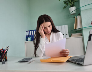 Unhappy woman touching forehead and holding paper reading bad negative news in letter at workplace