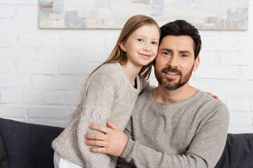 bearded man and preteen girl smiling and looking at camera at home.