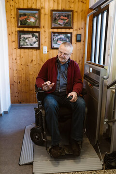 Full length of retired senior man with disability in motorized wheelchair at home