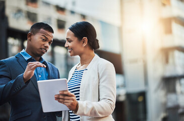 Building on their successful joint venture. Shot of two businesspeople using a digital tablet in...