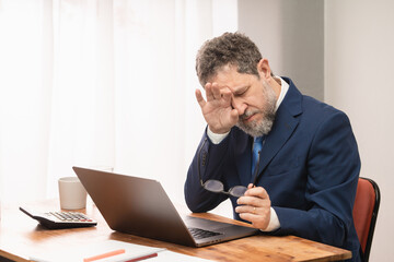 Businessman with Computer Struggling with Eyestrain - Stressed Middle-Aged Businessman Struggling...