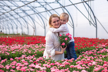 Mother and son in greenhouse with flowers in blossom. Eco lifestyle, family gardening