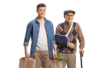 Young man helping an elderly man with a broken arm and carrying shopping bags