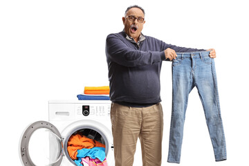 Shocked mature man taking out a pair of jeans from a washing machine