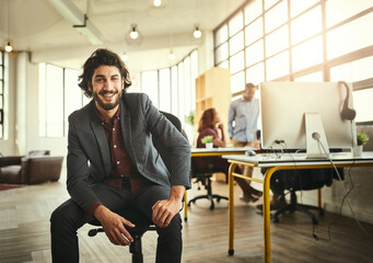 My innovation my increase productivity. Cropped portrait of a handsome young businessman sitting in the office with his colleagues in the background.