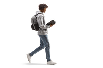 Full length profile shot of a young african american man walking and reading a book