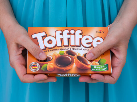 Tambov, Russian Federation - December 29, 2022 A box of Toffifee candies in woman hands against turquoise 