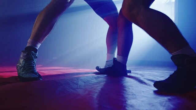 Two athletes wrestle in gyms preparing for competition. Men are engaged in martial arts and sports. Close-up of wrestlers legs on mat. High quality 4k footage