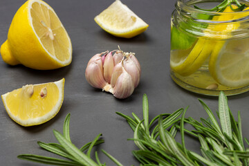 Rosemary sprigs, garlic and lemon on the table. Lemon drink in a glass jar.