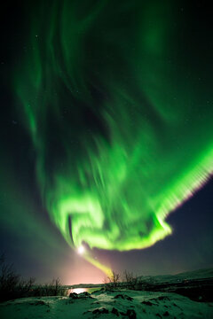 imagen de un paisaje nocturno nevado con una aurora boreal en el cielo de Islandia