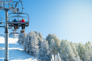 People on the chairlift enjoying the landscape and the snow doing outdoor sports in winter, skiing in a sunny ski resort