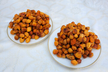 Piles of dried apricots, uryuk, placed on a plates on a cream coloured tablecloth, oriental sweets
