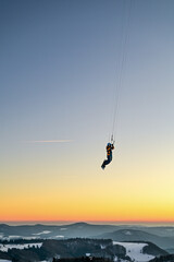 Snowkiting, Snowboarder fliegt mit Zugdrachen durch den Sonnenuntergang am Himmel der Wasserkuppe...