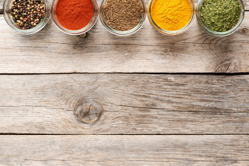 Colourful spices in bowls on wooden table with copyspace. Big collection of spices. Top view