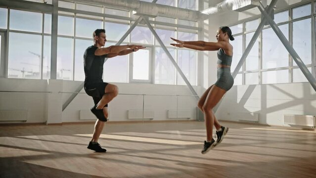 Slow motion of athletic couple face to face, jump up in the place for warm-up during workout indoor