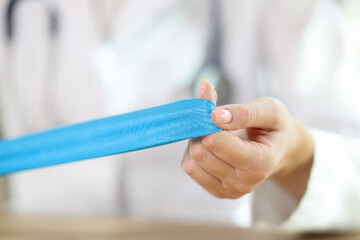 Woman physical therapist showing blue medical tape in hands