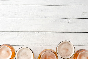 Collection of beer mugs on white wooden table with copyspace. Top view