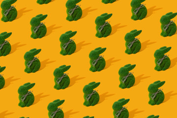 Pattern with green grass bunny toy on yellow background. Concept of Easter egg hunt.