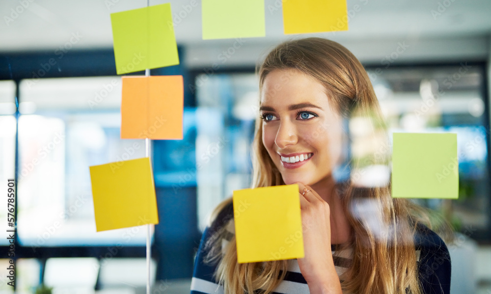 Poster Creativity is a process. Shot of a young woman having a brainstorming session with sticky notes at work.