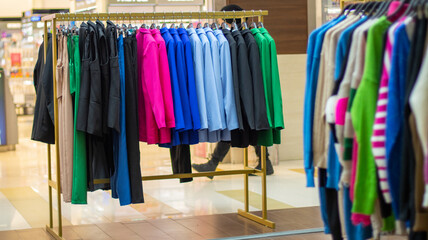 Rack of fashionable women's clothing, selective focus. Hangers in a row with bright women's...