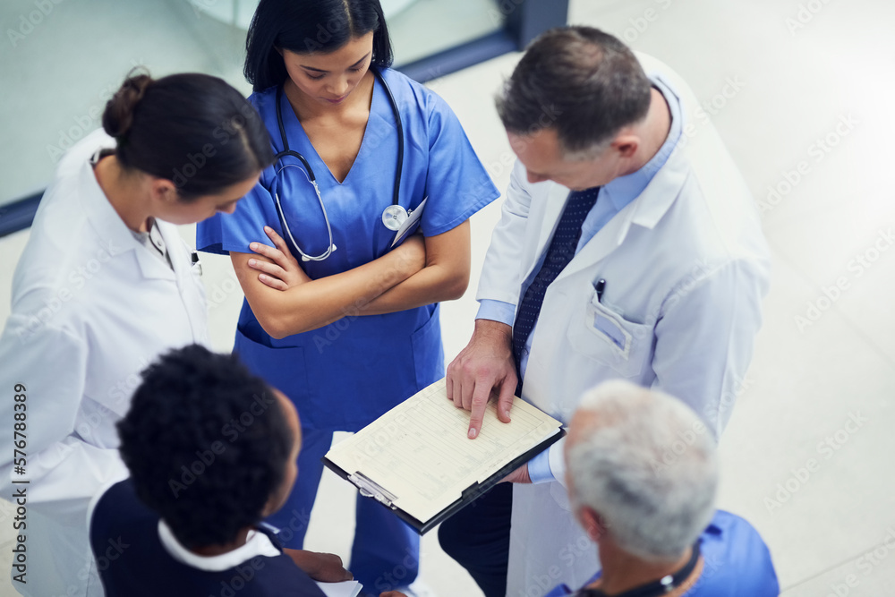 Poster lets up the dosage for this patient. shot of a group of doctors talking together over a medical char