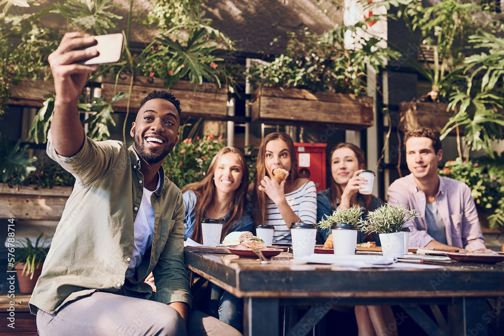 Poster lunchtime selfie with my besties. shot of a young man taking a selfie while out with friends at a ca