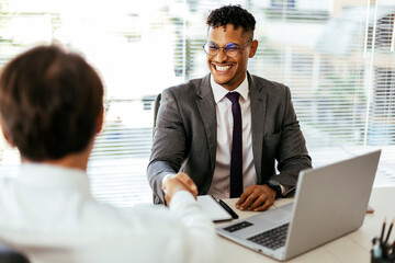 Sealing a deal. Close-up of two business people shaking hands while sitting at the working place