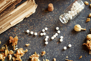 Homeopathic pills spilled from a bottle on a table