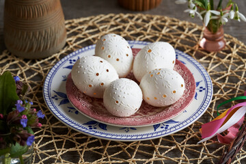 White Easter egg decorated with wax with spring flowers and pomlazka - Czech Easter whip