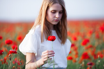 Unhappy teen girl with poppy flower in hand. Self-assessment, mental health and relationship...